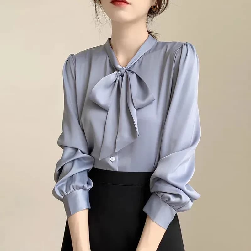 blue satin tie neck bow blouse worn tucked into a black skirt