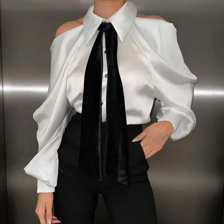 woman wearing a white satin cold shoulder shirt with a black tie and black trousers